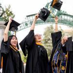 four students throw their caps in the air