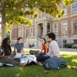 Several students studying together, sitting on the grass in front of South Hall