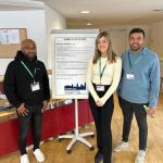 three people stand in front of a poster board