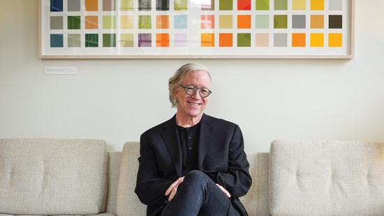 man with glasses sits on a white couch