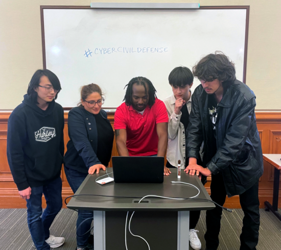 man surrounded by students around a computer