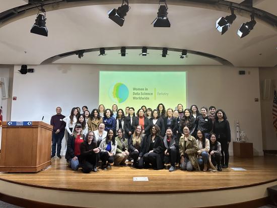 photo of a group posing on a stage in front of WiDS logo