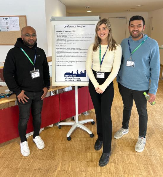 three people stand in front of a poster board