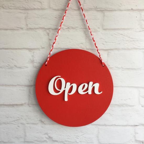 A sign reading "Open" hanging on a white wall.